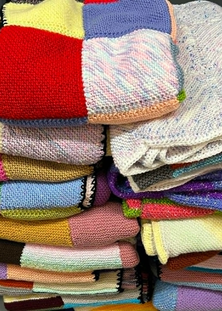 Pile of colourful handmade blankets showing our progress toward the 150 Blankets of Hope target, with 60 blankets completed so far.