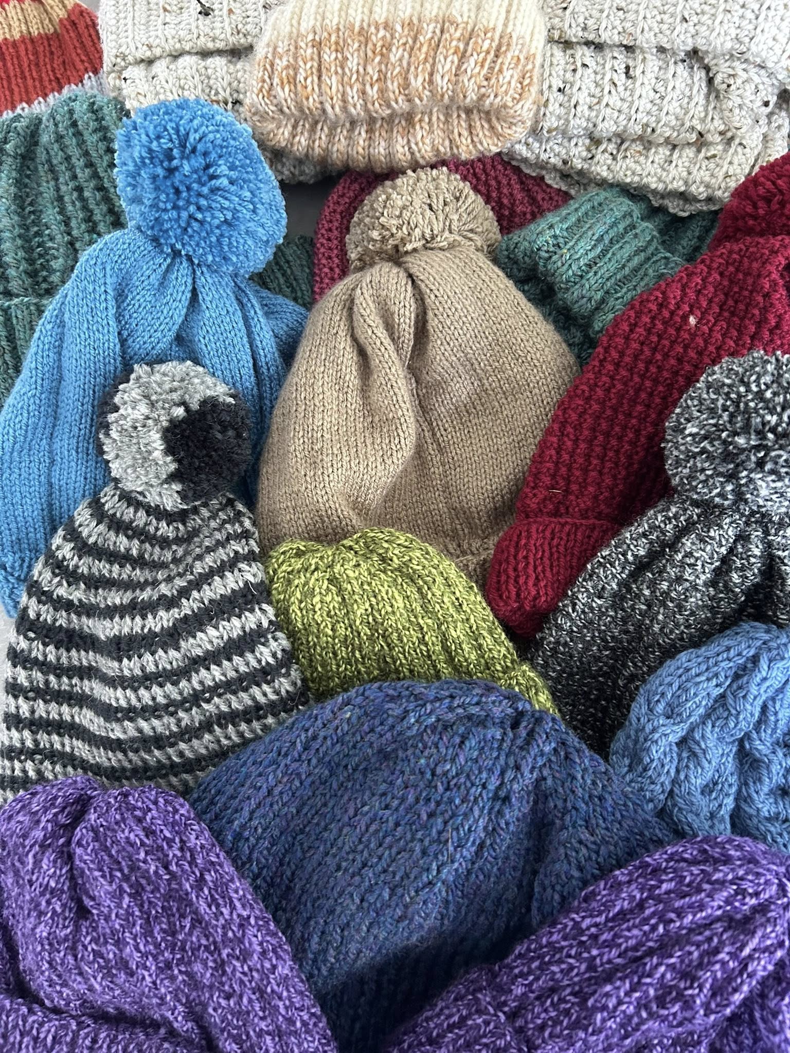 Handknitted hats made by Swindon Big Knit, featuring a colourful mix of yarns and styles created by community volunteers.