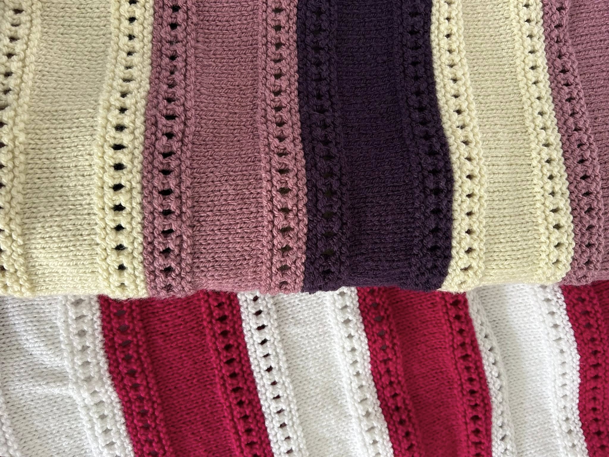 Close‑up of hand‑knitted striped blankets with lace‑style stitch patterns in soft, coordinating colours.
